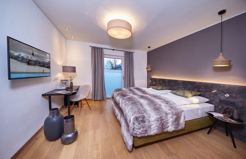 modernes Doppelzimmer mit Bett, Schreibtisch und Fernseher