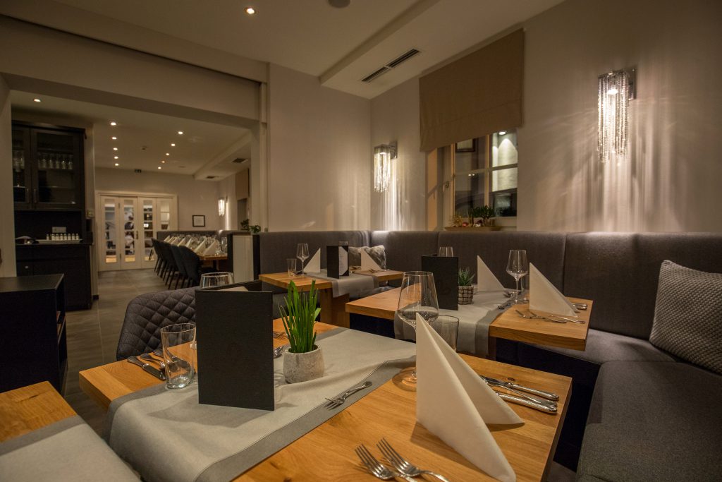 modern eingerichtetes Restaurant mit gedeckten Holztischen