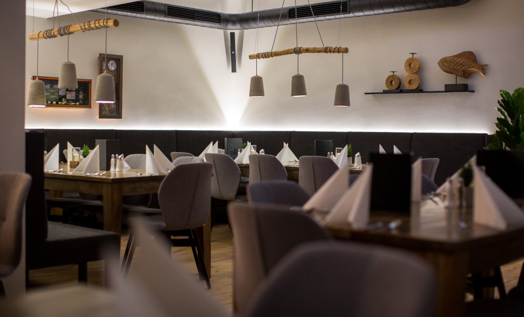 modernes Restaurant mit gedeckten Holztischen und grauen Stühlen