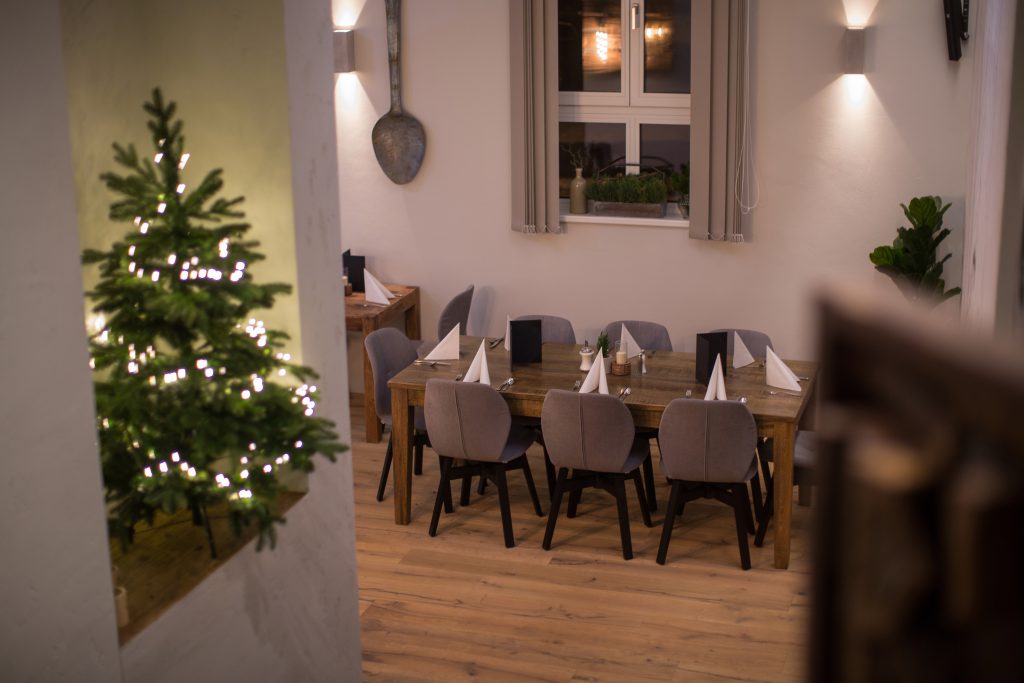 gedeckter Holztisch in modernem Restaurant mit Weihnachtsbaum